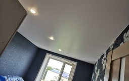 Белый сатиновый потолок в спальню со светильниками.